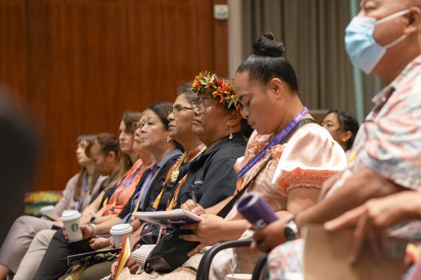 Attendees following a session from the front rows, one taking notes