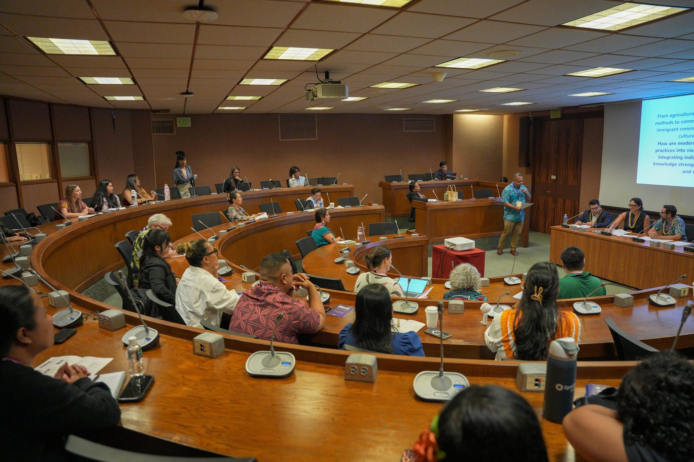 A breakout session in a tiered room with microphones at every seat