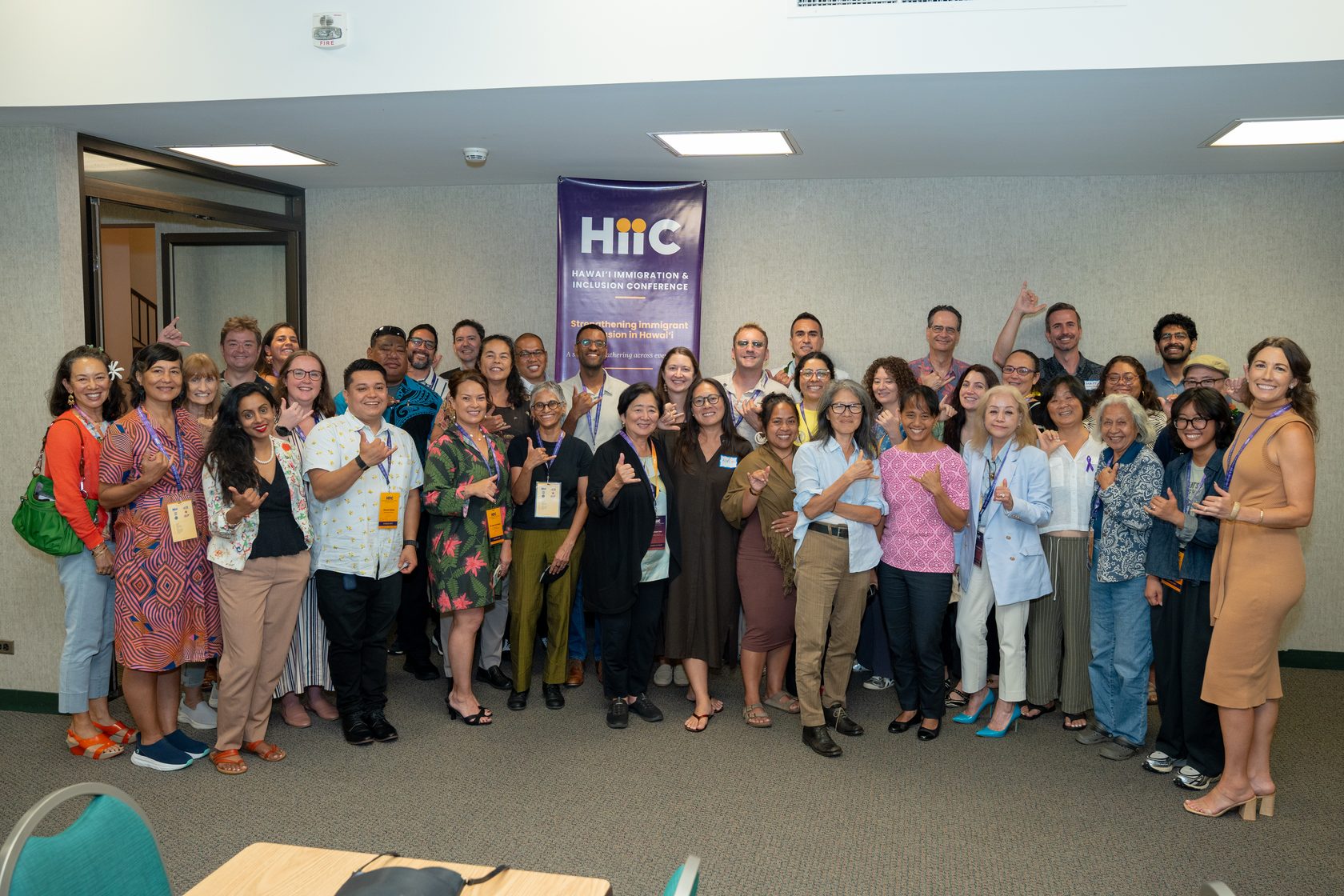 Attendees throwing shakas in a group photo under the HIIC banner